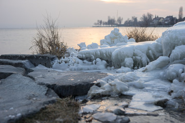 icy coast on lake of constance with sunset
