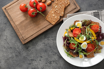 Salad with cherry tomatoes and quail eggs served on white plate, top view