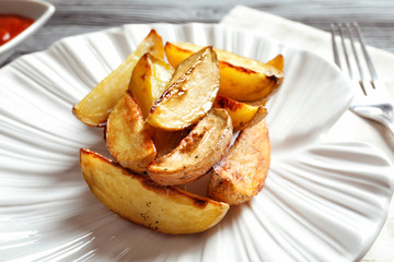 Plate with delicious baked potato wedges, closeup