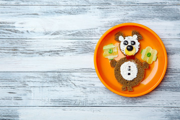 Funny food idea for kid breakfast on wooden background