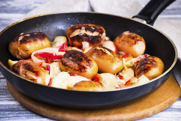 Fried pork sausages with apples and onions in a frying pan