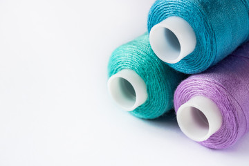 Sewing supplies and accessories for needlework. coils of blue green purple violet lilac thread for sewing clothes on white background.