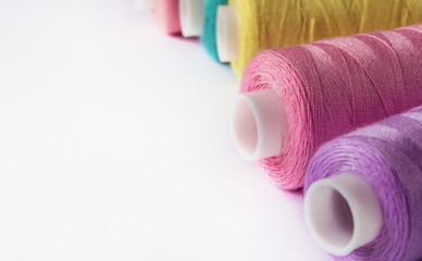 Sewing supplies and accessories for needlework. coils of yellow pink violet lilac thread for sewing clothes on white background.