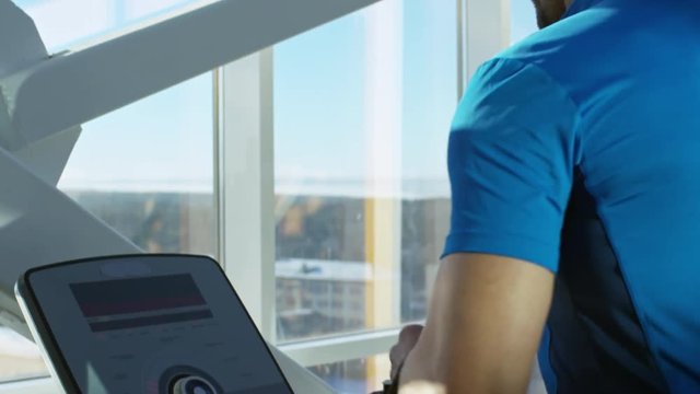 Close up of man jogging on treadmill at the gym and monitoring information he sees on the screen