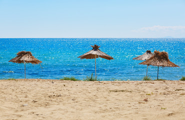 Thatched beach umbrellas. Blue sea and clear sky. Straw parasols.