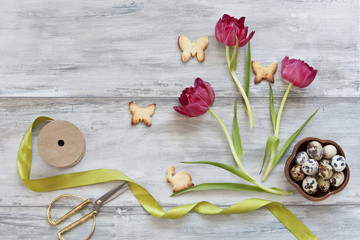 Close-up of cute bunny cookies with pink tulips flowers on grey wooden vintage background. Easter concept