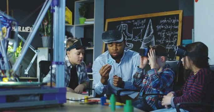 Black man with group of kids having lesson about 3d modeling wearing VR glasses in lab. Movement 4K shot on Red cinema camera.
