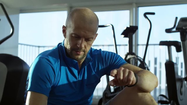 Mature man doing twist crunches and using smartphone to see his training program