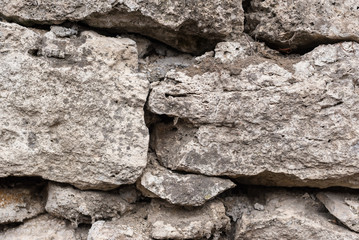 Close-up textured background is an irregular natural stone wall made of different stones without a cement-type bonding mixture. Medieval background