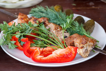 In a white plate are fresh vegetables with meat cooked on the grill.