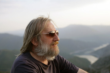 Fototapeta premium Man portrait; portrait of a bearded man with sunglasses in nature.