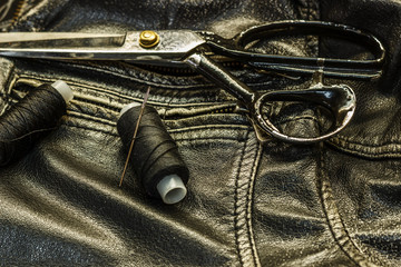 Sewing leather jacket, repair of leather jacket scissors, thread, close-up. Products of leather.