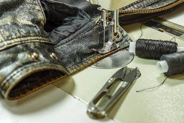 Sewing leather jacket repairing leather jacket scissors, thread, sewing machine, close-up.