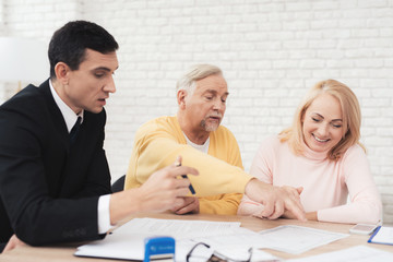 A couple of old people at a reception with a realtor. They are satisfied with the service.