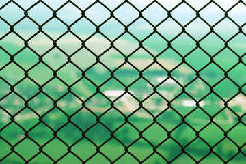 Fototapeta premium Protective restrictive metal mesh on top of the mountain. Beautiful view of the green summer valley from the top of the mountain