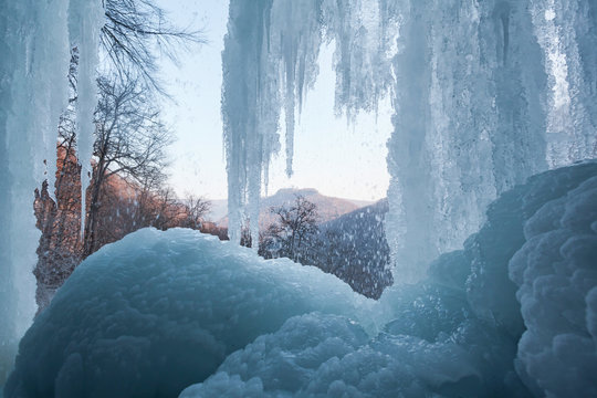 Bad Urach Wasserfall mit Eis und Blick auf die Burgruine Hohenurach.  In der Eishöhle unter den Eiszapfen.