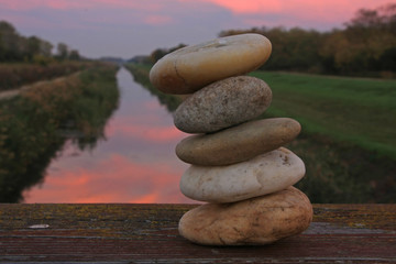 gestapelte steine vor landschaft mit fluss, vor morgendlichem himmel
