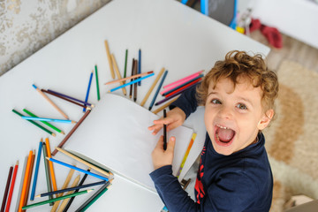 little boy paints greeting card with colour pencils and smile