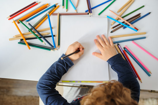 little boy paints greeting card with colour pencils