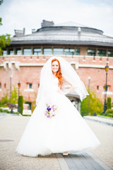 Fototapeta premium Beautiful red haired bride perfect style. Wedding hairstyle make-up luxury wedding dress and bride's bouquet.