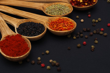 Spice. Spice in a wooden spoon. Herbs. Curry, saffron, turmeric, pepper and others on a black background.