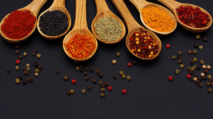Spice. Spice in a wooden spoon. Herbs. Curry, saffron, turmeric, pepper and others on a black background.