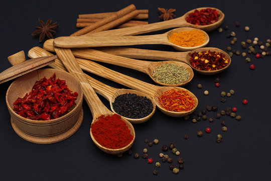 Spice. Spice in a wooden spoon. Herbs. Curry, saffron, turmeric, pepper and others on a black background.