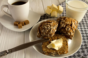 Breakfast:buns with sunflower seeds,coffee  and milk  on the white  wooden background