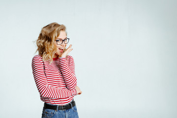 The lovely girl the blonde in stylish glasses poses on a white background. Emotions. Body language....