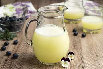 A jug of fresh whey with two glasses and blueberries