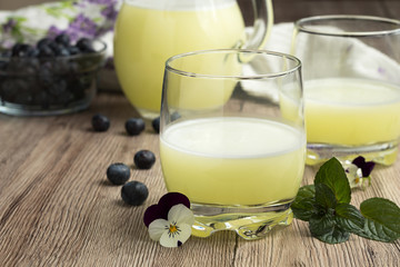 A glass of fresh whey with a jug of whey and blueberries