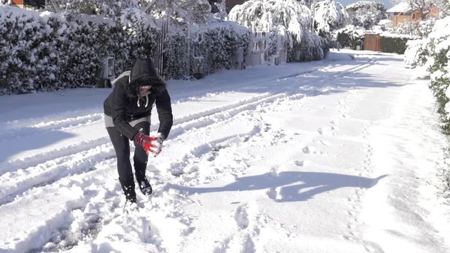Happy woman throwing snow ball playing with kids slow motion