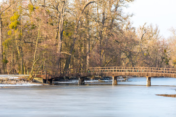 Fototapeta na wymiar Small bridge on the winter lake, trees and forest