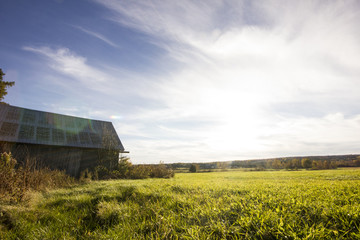 Obraz premium Barn standing in a field with a blue sky.