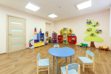 Blue table for classes with children and light pink colored game room with in the kindergarten