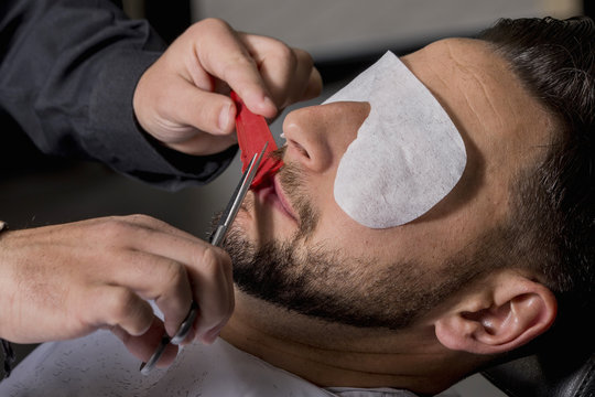 Hairdresser shaving his beard with scissors to a client
