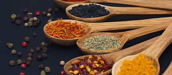 Spice. Spice in a wooden spoon. Herbs. Curry, saffron, turmeric, pepper and others on a black background.