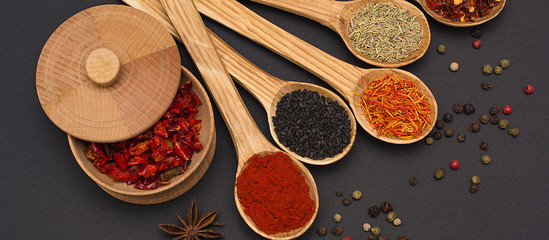 Spice. Spice in a wooden spoon. Herbs. Curry, saffron, turmeric, pepper and others on a black background.
