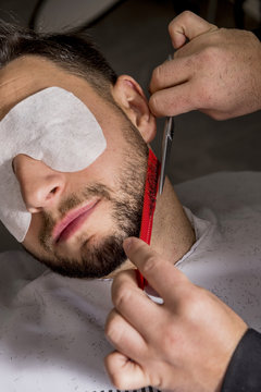 Hairdresser shaving his beard with scissors to a client