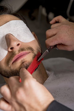 Hairdresser shaving his beard with scissors to a client