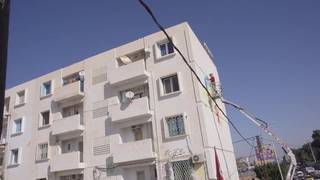 artist painting a wall mural in a cherrypicker