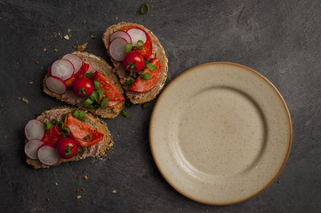 sandwich with vegetables and salami on a black table, healthy food. 
