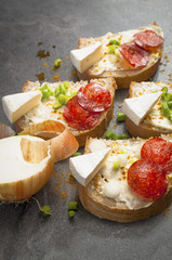 sandwich of spicy salami and cheese on a black wooden table.