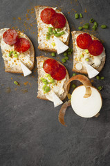 sandwich of spicy salami and cheese on a black wooden table.