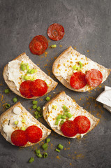sandwich of spicy salami and cheese on a black wooden table.