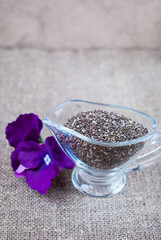 Chia seeds in glassware with purple flowers on a linen tablecloth