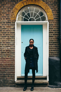 Beautiful African woman standing in frornt of a door to a property.