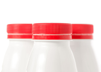 Three plastic white bottles with yoghurt kefir milk