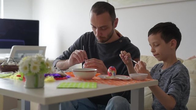 Child with his father paint traditional Easter eggs