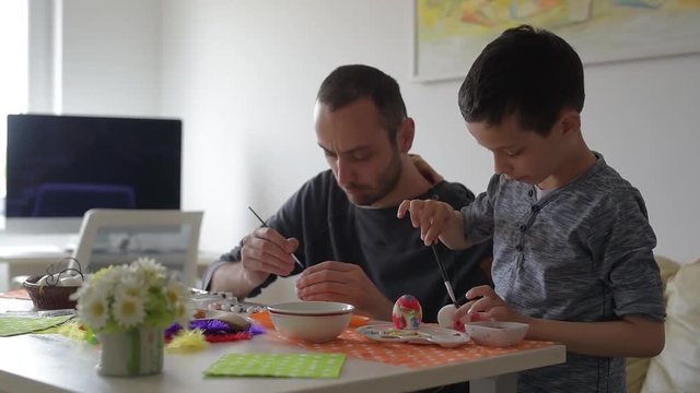 Child with his father paint traditional Easter eggs